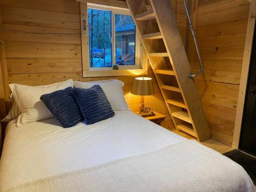 Un dormitorio con una cama con almohadas azules y una escalera en Ski-In Chalet: Private Hot tub, Bonus Bunk House, en Fernie
