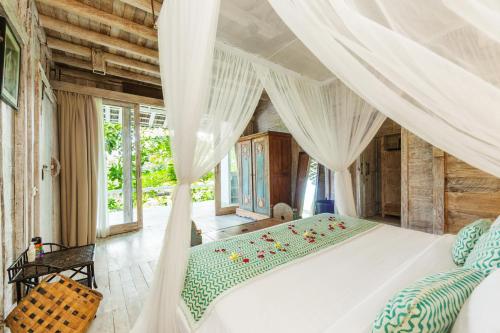 a bedroom with a white bed with a canopy at Villa Sungai Laut in Canggu