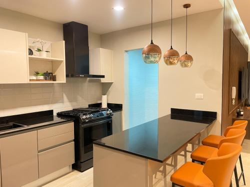a kitchen with a black counter top and orange chairs at Luxurious Modern Apartment Piantini Near Blue Mall in Santo Domingo