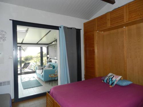 Schlafzimmer mit einem lila Bett und einer Glasschiebetür in der Unterkunft Appartement Le Lavandou, 2 pièces, 4 personnes - FR-1-251-792 in Le Lavandou