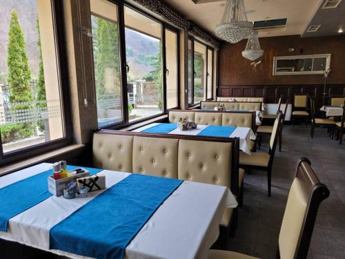 un comedor con mesas, sillas y ventanas en Хотел “Райски кът” en Cheresha