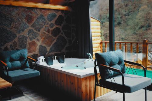 a jacuzzi tub on a porch with two chairs at Golden Rose Bungalov in Ardeşen