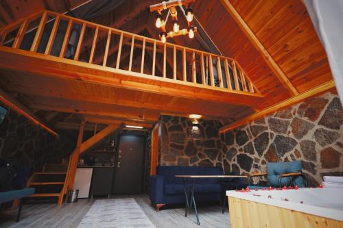 a living room with a staircase and a stone wall at Golden Rose Bungalov in Ardeşen
