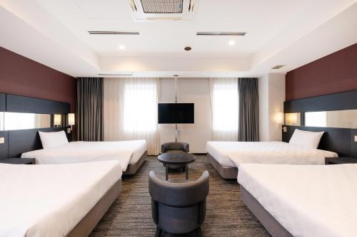 a hotel room with four beds and a tv at The OneFive Osaka Namba Dotonbori in Osaka