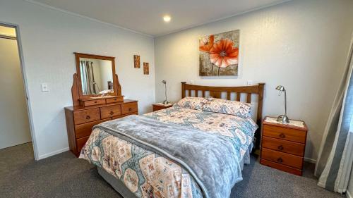 1 dormitorio con cama, tocador y espejo en Mosaic Cottage - Napier Holiday Home, en Napier