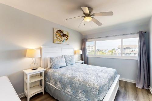 a bedroom with a bed with a ceiling fan and a window at Oceanfront Oasis in Emerald Isle