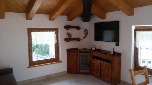a living room with a flat screen tv and two windows at Mansarda Monte Bianco in La Salle