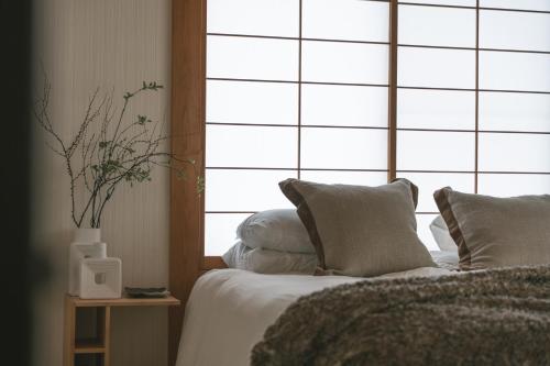 a bedroom with a bed with pillows and a window at Shofusha Lodge Madarao Tangram in Madarao Kogen
