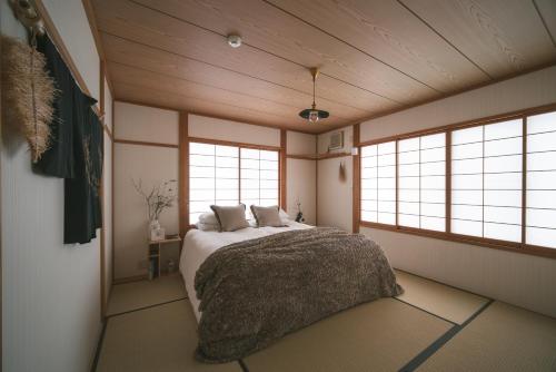 Shofusha Lodge Madarao Tangram في Madarao Kogen: غرفة نوم بسرير ونوافذ