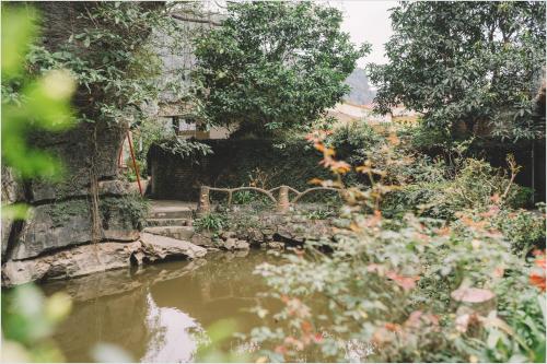 un jardin avec un étang, des arbres et des fleurs dans l'établissement Trang An Mountain House, à Ninh Binh