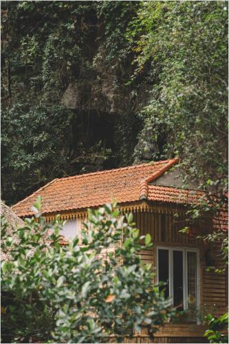 a house with a tiled roof next to a mountain at Trang An Mountain House in Ninh Binh
