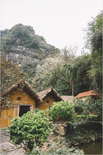 a wooden house with a mountain in the background at Trang An Mountain House in Ninh Binh