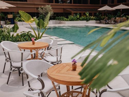 two tables and chairs next to a swimming pool at Nysa Hotel Bangkok Sukhumvit 11 in Bangkok