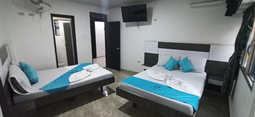 - une chambre avec 2 lits avec des oreillers bleus et une télévision dans l'établissement Hotel Sol Del LLano, à Villavicencio