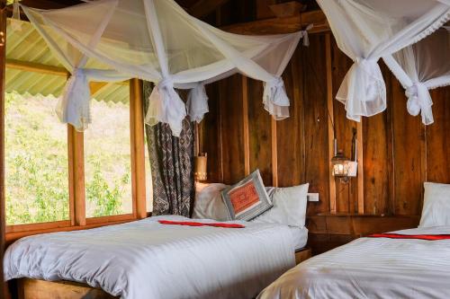 1 dormitorio con 2 camas y ventana en Hoa Lan Bungalow & Restaurant, en Phong Thổ