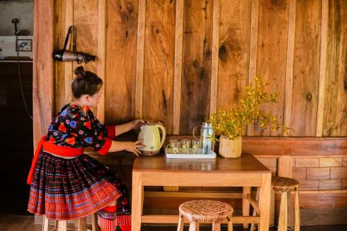 une femme debout à une table avec une bouilloire dans l'établissement Hoa Lan Bungalow & Restaurant, à Phong Thổ