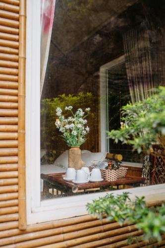 a window with a table with cups and flowers on it at Trang An Mountain House in Ninh Binh