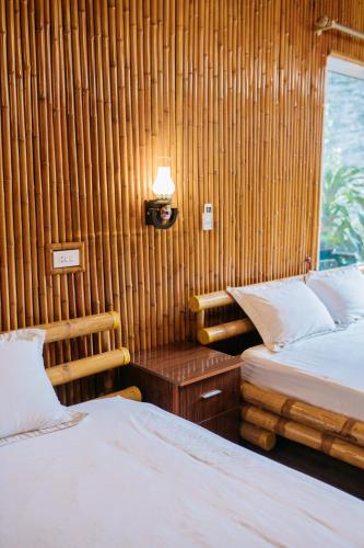 a bedroom with two beds and a table with a lamp at Trang An Mountain House in Ninh Binh
