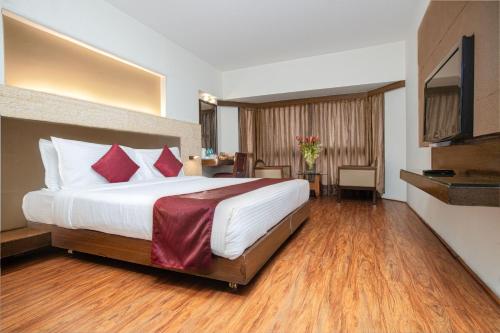 a hotel room with a large bed with red pillows at Monarch Brigade Road in Bangalore