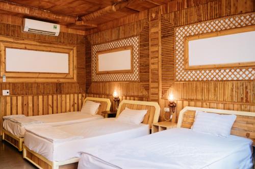 two beds in a room with wooden walls at Trang An Mountain House in Ninh Binh