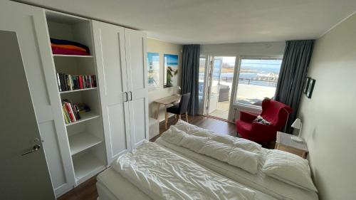 a small bedroom with a bed and a red chair at Takvåning - Borgholm in Borgholm