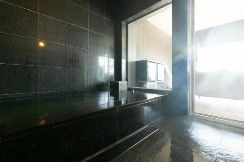 ein schwarz gefliestes Bad mit einem großen Fenster in der Unterkunft 御宿 白金の森 in Kikuchi