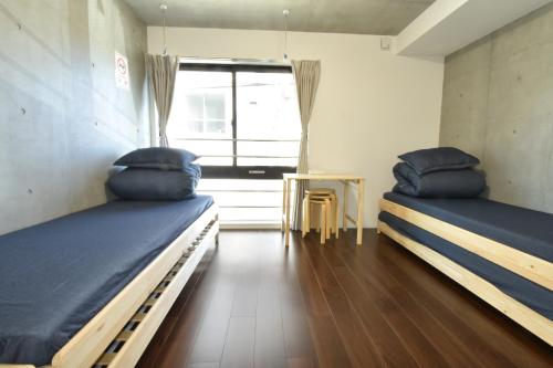 2 camas en una habitación con ventana y mesa en Enzo iogi, en Tokio
