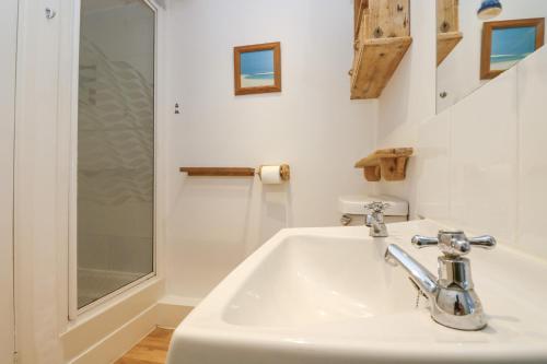 un baño con lavabo y ducha en Cockle Island Cottage, en Porthallow
