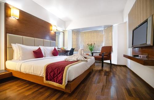 a hotel room with a bed and a television at Monarch Luxur - Infantry Road in Bengaluru