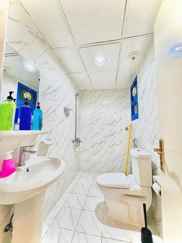 a white bathroom with a toilet and a sink at DSV Property in Abu Dhabi