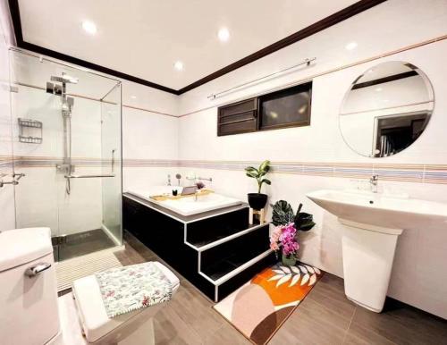 ein Badezimmer mit zwei Waschbecken, einer Badewanne und einer Dusche in der Unterkunft 高尔夫泳池花园6卧高端别墅 in Ban Huai Yai