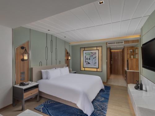 a bedroom with a large bed and a flat screen tv at Nysa Hotel Bangkok Sukhumvit 11 in Bangkok