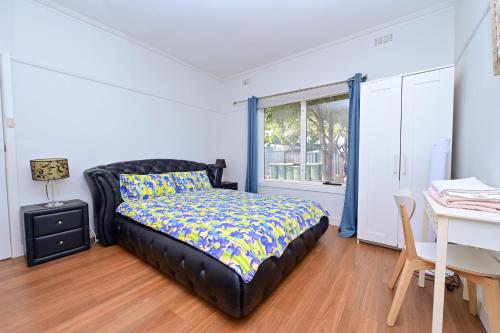 a bedroom with a bed and a desk and a window at Classic decor, freshly painted 3 by 2 quiet home in Corio