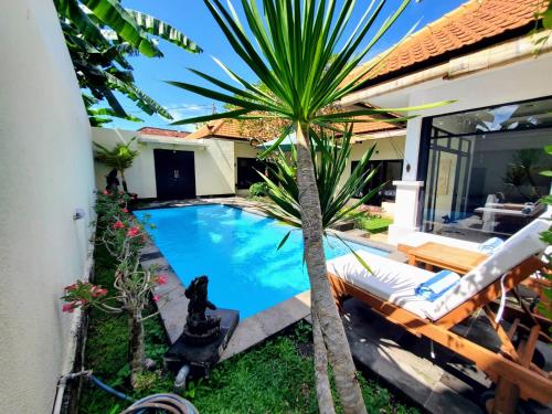 - une piscine dans l'arrière-cour d'une maison avec un palmier dans l'établissement Villa BeBe, à Canggu