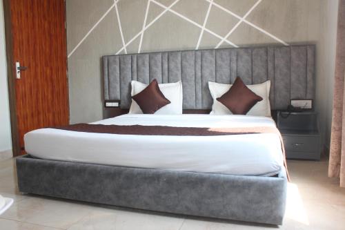 1 dormitorio con 1 cama grande y cabecero gris en The Desi Rootz Hotel And Restaurant, en Rāmnagar