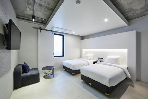 a bedroom with two beds and a chair at Hotel Intro in Busan