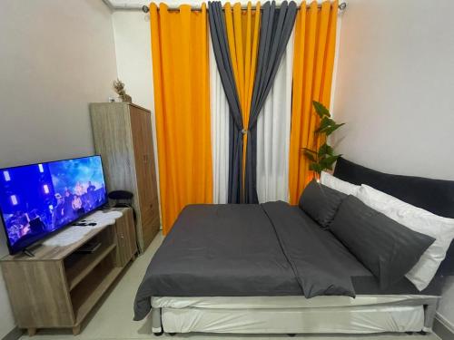 a bedroom with a bed and a desk with a television at South Residences in Manila