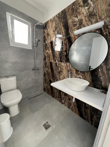 a bathroom with a toilet and a sink and a mirror at Nikos studios in Livadia