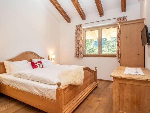 1 dormitorio con cama de madera y ventana en BergChalet Breitenberg, en Bad Hofgastein