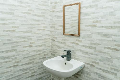 un lavabo blanc dans une salle de bain avec un miroir dans l'établissement Kayuma Hostel Canggu, à Canggu