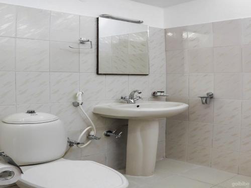 a white bathroom with a toilet and a sink at Hotel Elegant in Dimāpur