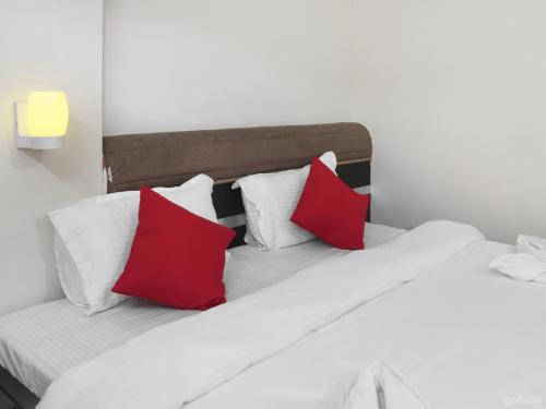 Una cama con almohadas rojas y blancas. en Hotel Elegant, en Dimāpur