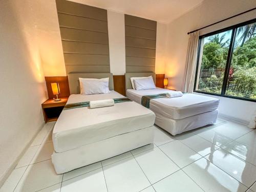 2 camas en una habitación con ventana grande en LA CASA BORNEO, en Bentakan Kecil