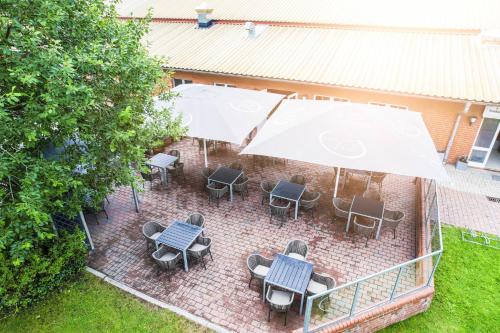 einen Blick über eine Terrasse mit Tischen, Stühlen und einem Sonnenschirm in der Unterkunft Hökis-Zimmervermietung 1 in Brande-Hörnerkirchen