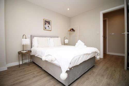 a white bedroom with a large bed with white pillows at Casablanca 18 - Cardiff Bay - 2 Bed Apartment in Cardiff