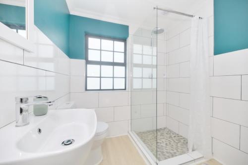 a white bathroom with a sink and a shower at House 15 A Kassiesbaai in Arniston