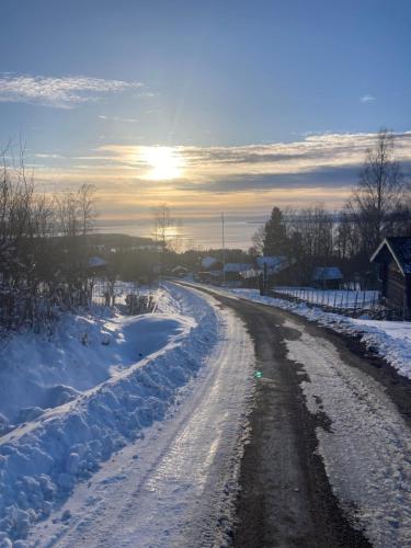 a snow covered road with the sun in the distance at Villa Franca Maria in Rättvik