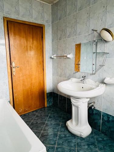 baño con lavabo blanco y puerta de madera en Goza Guest House 22 en Addis Abeba