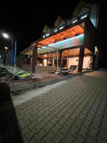a lit up building at night with chairs in front at Gasthaus Casa Kugler in Anina