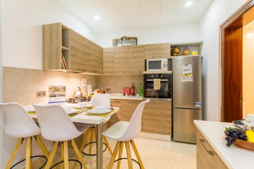 eine Küche mit weißen Stühlen, einem Tisch und einem Kühlschrank in der Unterkunft Sunny Maltese townhouse Madonnina Kalkara - Happy Rentals in Kalkara